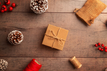 hristmas gift box positioned on rustic wooden surface with berries and cones, great for winter promotions, product advertising, greeting cards and festive layouts