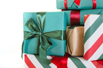 Close-up of a stack of wrapped Christmas gifts on a wooden stool against white background.