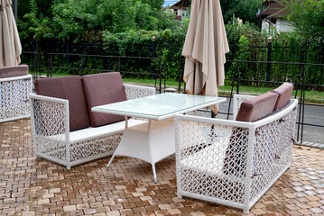 Outdoor wicker furniture set with glass table on patio.