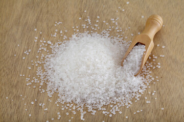 White sugar spilled out of wooden scoop