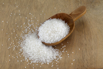 White sugar spilled out of wooden scoop
