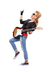A rocker girl in ripped jeans poses for the camera with an electric guitar