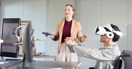 After introducing VR, female coworker demonstrating VR simulation at desk guiding male headset user