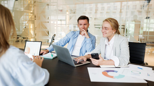 Team discussion over digital devices in modern office - Powered by Adobe