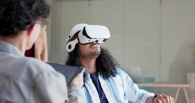 Diverse coworkers in office lounge tapping tablet guiding VR headset user testing controls