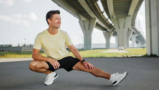 Man stretching under a bridge while preparing to exercise