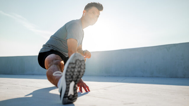 Man stretches in urban setting during fitness routine - Powered by Adobe