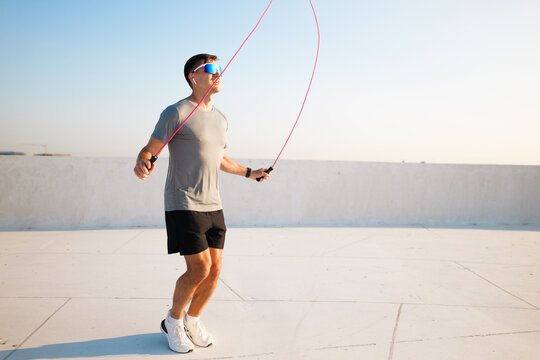 Man skipping rope on rooftop during workout session - Powered by Adobe