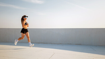 Woman jogging on a white path in sunny weather