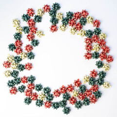 Red, green and gold tiny, gift bows forming a circle or wreath shape on white background