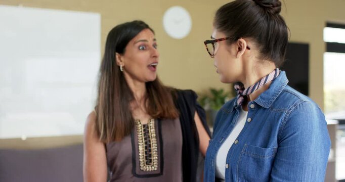 Diverse female coworkers tapping tablet screen sparking project goal discussion at office lounge - Powered by Adobe