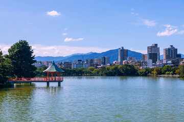 Fototapeta premium hexagonal red pavilion from Ohori lake park with Fukuoka town view