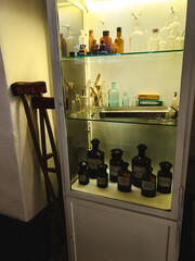 Antique Illuminated Pharmacy Cabinet with Glazed Shelves, Old Bottles and Containers with Labels and Wooden Invalid Balls