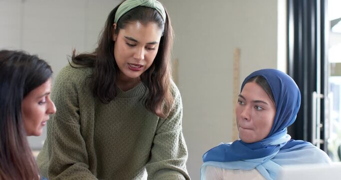 Diverse female colleagues sparking talk by presenting project on tablet at table while holding mug