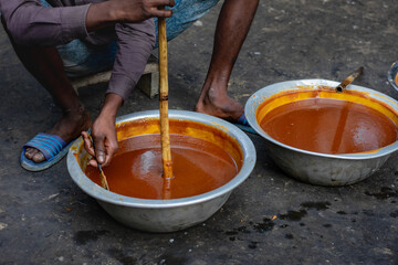 Artisanal Jaggery Making: Worker Stirring the Thickened Molasses Before Cooling