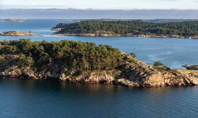 Kristiansand, Norway-August 12, 2025: Rocky Coastline With Dense Forest and Calm Bay