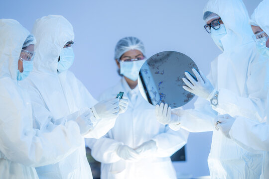 Semiconductor specialists analyzing silicon wafer for high-performance AI processor fabrication and nanotech supply chain solutions.