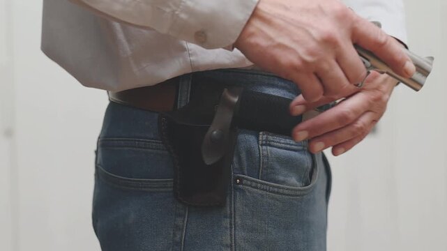 Detail of human with handgun indoor at home drawing his weapon
