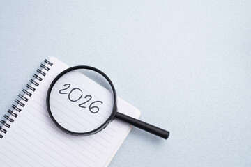 Happy New Year 2026 and a notepad on a colored background. Layout for writing annual business plans, schedules, as well as New Year's resolutions and goals.