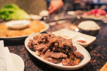 A Korean BBQ grill table being used at a KBBQ food restaurant with hands 
