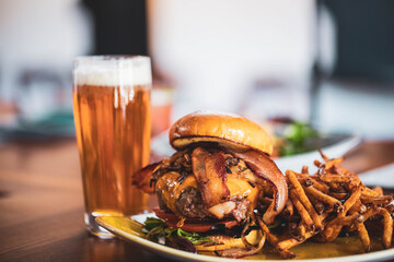 A bacon cheeseburger with fries and a beer at a modern American restaurant and bar pub