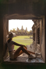 Woman Sitting Inside Temple Window Looking at Angkor Wat at Sunset