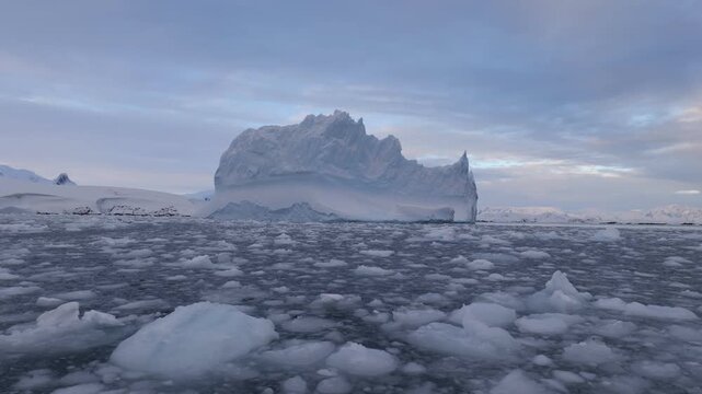 Stunning Antarctic landscape with icebergs and mountains in the background, scattered with numerous small icebergs across the icy waters. Dramatic polar scenery. 4K video.