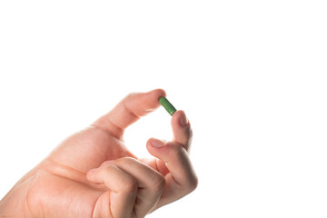 Detailed close-up of a male hand pinching a green capsule. Focus on the texture and color, suitable for pharmaceutical and medical articles.