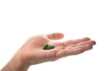 Male hand showing an open palm with three vitamin pills (green and beige). Represents variety in...