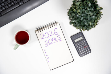 Office desk with 2026 Goals notepad and a calculator. Concept of financial freedom, savings, investment strategy, and economic planning for the new year.