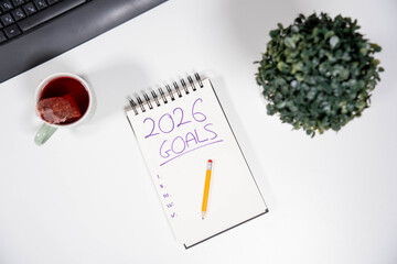 Top view of an office desk with a 2026 Goals list, computer keyboard, and tea. Concept of career planning, business strategy, and future corporate ambitions.