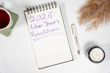Handwritten 2026 New Year's Resolutions on a notepad with aesthetic dried grass and a candle. Concept of personal growth, mindfulness, and future planning.