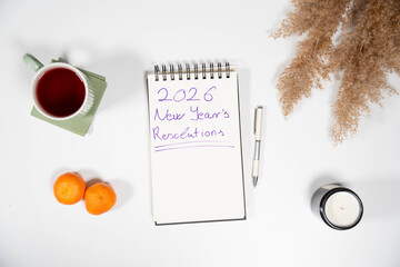 2026 New Year's Resolutions notebook with fresh tangerines and tea. Symbolizes health goals, diet changes, and a fresh start for the upcoming year.
