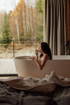 Enjoying a relaxing moment in a modern bathtub with a cup of tea