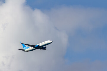 Passenger airliner in white and blue colors taking off against a blue sky with clouds. Commercial...