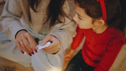 A child and an adult joyfully craft paper snowflakes at home, preparing for Christmas and the New Year with holiday spirit in a cozy atmosphere.