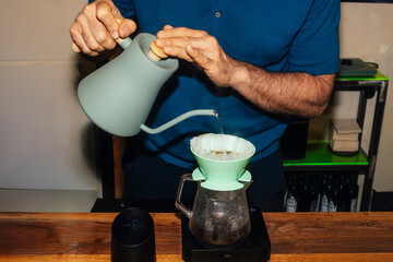 Barista pouring water into coffee dripper.