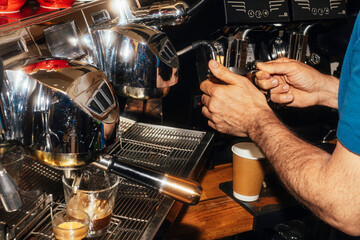 Barista steaming milk at espresso machine.