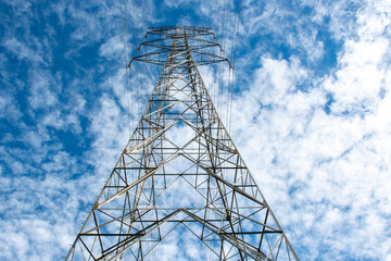 Torres de transmisión eléctrica de alta tensión en un campo abierto bajo un cielo azul y nubes...