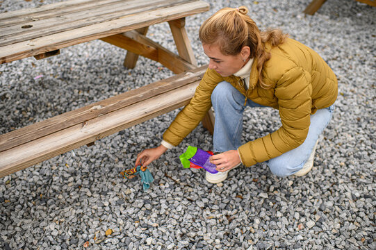 Woman  picking up litter in a public park, collecting trash in bags as part of a community clean-up, promoting environmental awareness and sustainable family activities. - Powered by Adobe