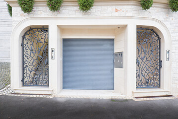 Luxury entrance to the house with roll-up garage doors and two wrought iron doors.