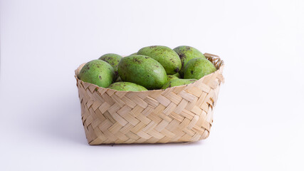 Basket full of fresh green mangoes on white background, highlighting tropical fruit, healthy ingredients, Asian food, and organic farm produce.
