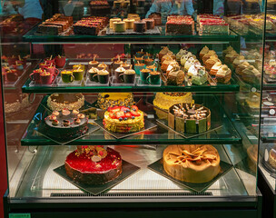 Closed glass window with sweet cakes on shelves inside pastry shop