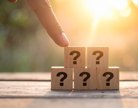 Wooden Blocks with Question Marks Against a Dramatic Sunset and Cloudy Sky