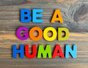 "BE A GOOD HUMAN" Motivational Quote with Colorful Block Letters on Dark Wooden Background: Kindness and Ethics Concept