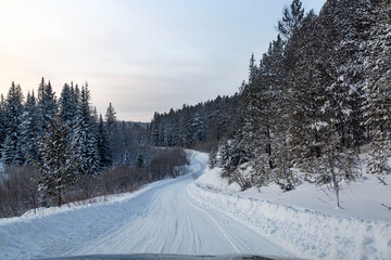 Winter landscape, road through a snowy forest. Winter travel.