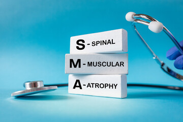 SMA, spinal muscular atrophy. Health concept. Text on white blocks. Blue background, stethoscope....