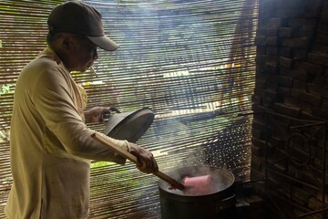 Brown-skinned Asian man boiling water in the kitchen, traditional Indonesian daily culture