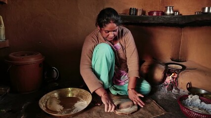 A poor indian woman in traditional Indian attire kneads dough beside a clay oven, preparing flatbreads in a cozy, rustic kitchen. Simple utensils, a wood-fired stove, and everyday family life set the 