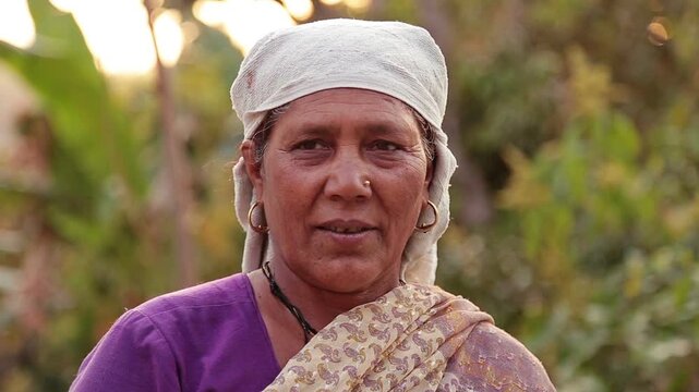 A portrait of an Asian woman from an Indian village, aged around 60&ndash;65 years, looking directly at the camera with a calm, neutral expression, reflecting authenticity, depth, and the quiet dignity of e